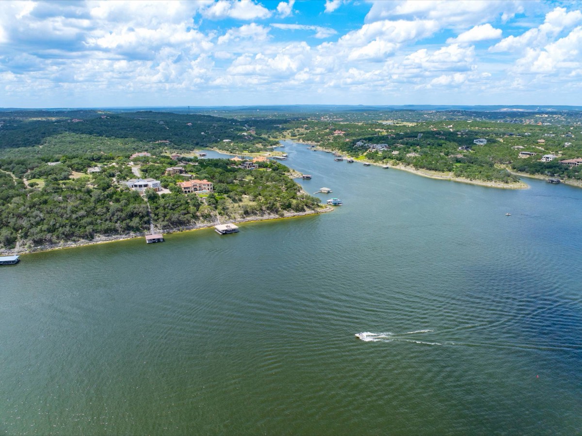 Aerial view of Lake Travis with lakefront homes, boat docks and Hill Country under a summer sky